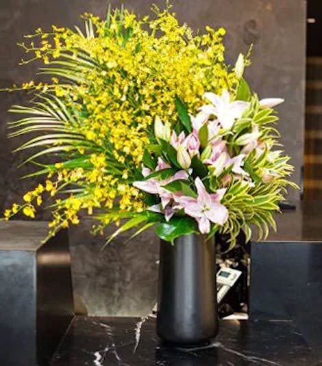 A lush mix of pink, green and gold flowers at the reception desk of a large corporation
