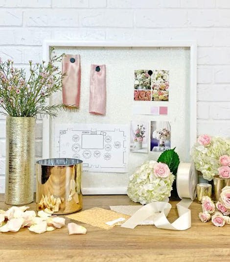 A floral designer's working space, scattered with sketches, fabric samples and flowers