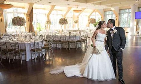 A bride and groom kissing on the floor of an empty reception hall